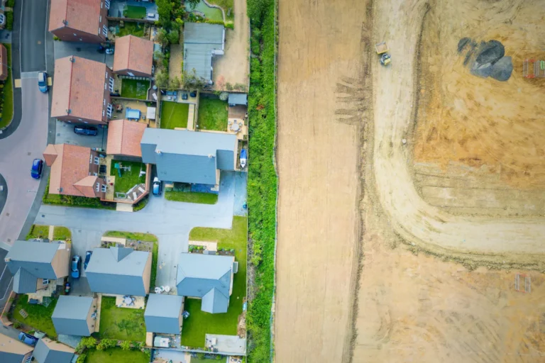 Aerial view showing residential homes next to a large cleared construction site