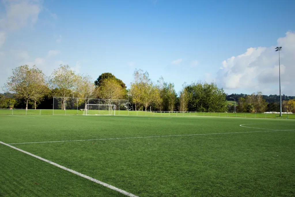 Empty football pitch with goalposts and green grass under a clear blue sky