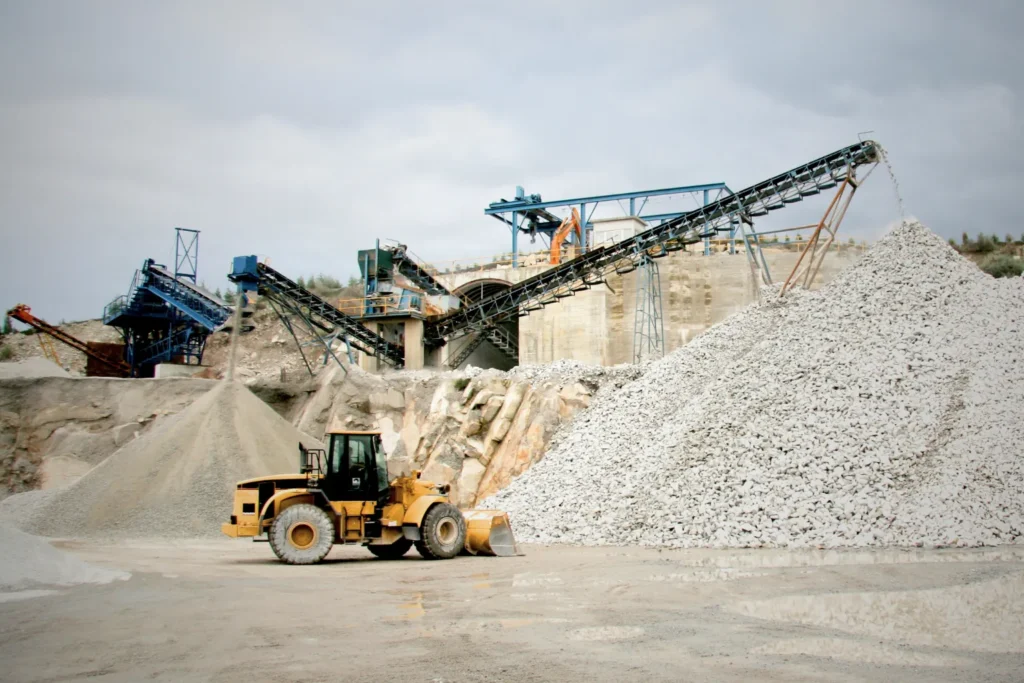 Loader working at quarry with gravel piles and conveyor systems