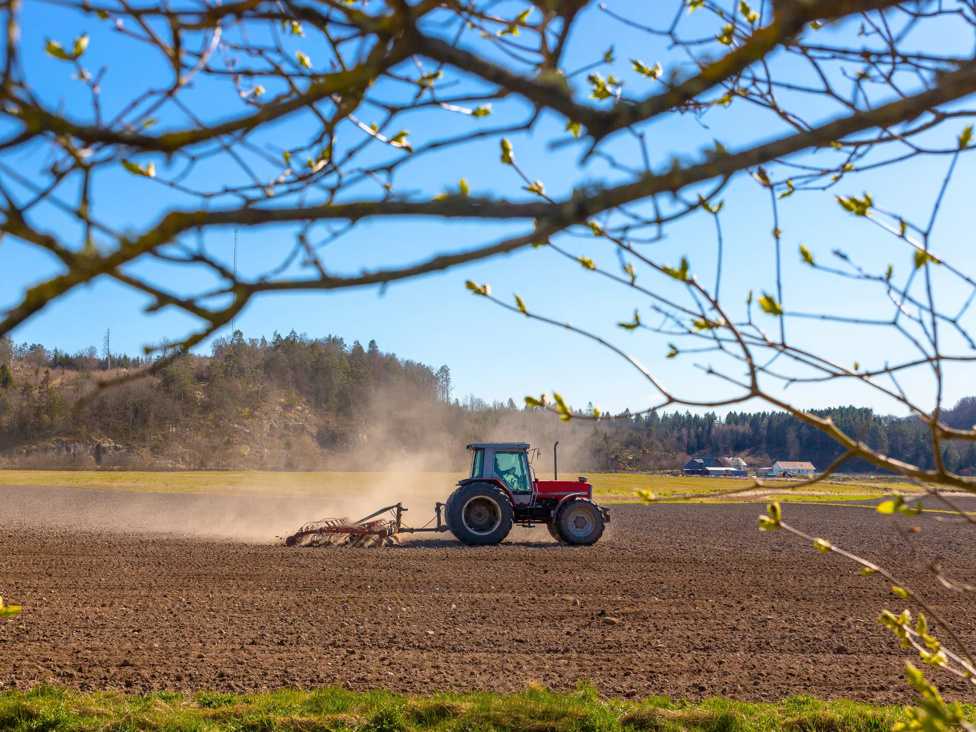 image of a tractor ploughing a field with dust rising behind it